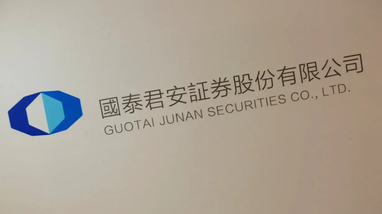 FILE PHOTO: A logo of Guotai Junan Securities is displayed at a news conference in Hong Kong