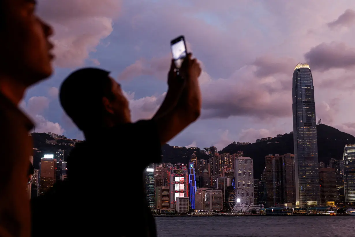 Chinese visitor takes a photo in front of Victoria Harbour, with the Central financial district in the background, as typhoon Yagi approaches in Hong Kong