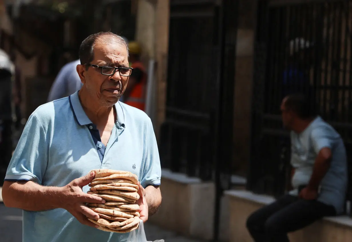 An Egyptian man carries bread bought from a bakery in Cairo