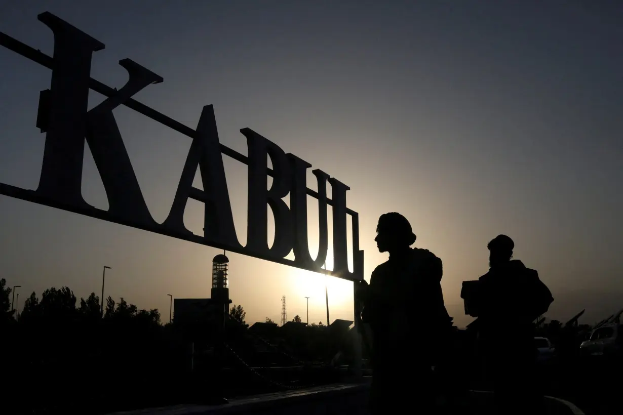 FILE PHOTO: Taliban soldiers stand in front of a sign at the international airport in Kabul