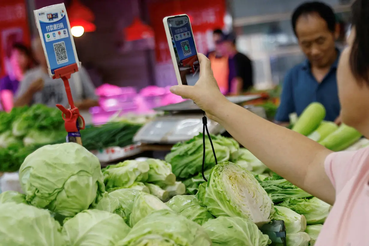 FILE PHOTO: Customer scans a QR code to pay for vegetables at a morning market in Beijing