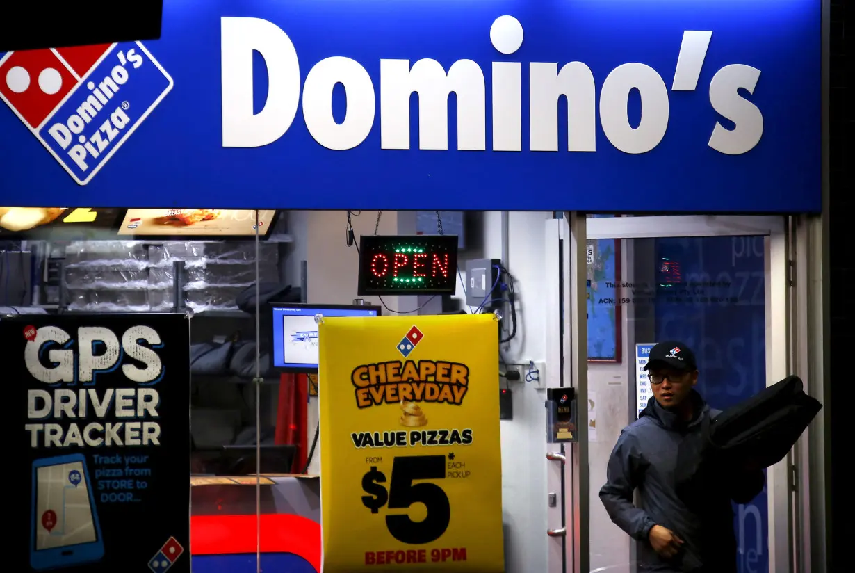 FILE PHOTO: A worker carries a pizza for delivery as he exits a Domino's pizza store in Sydney, Australia