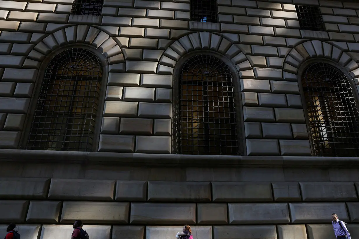 FILE PHOTO: People walk by the Federal Reserve Bank of New York in the financial district of New York City