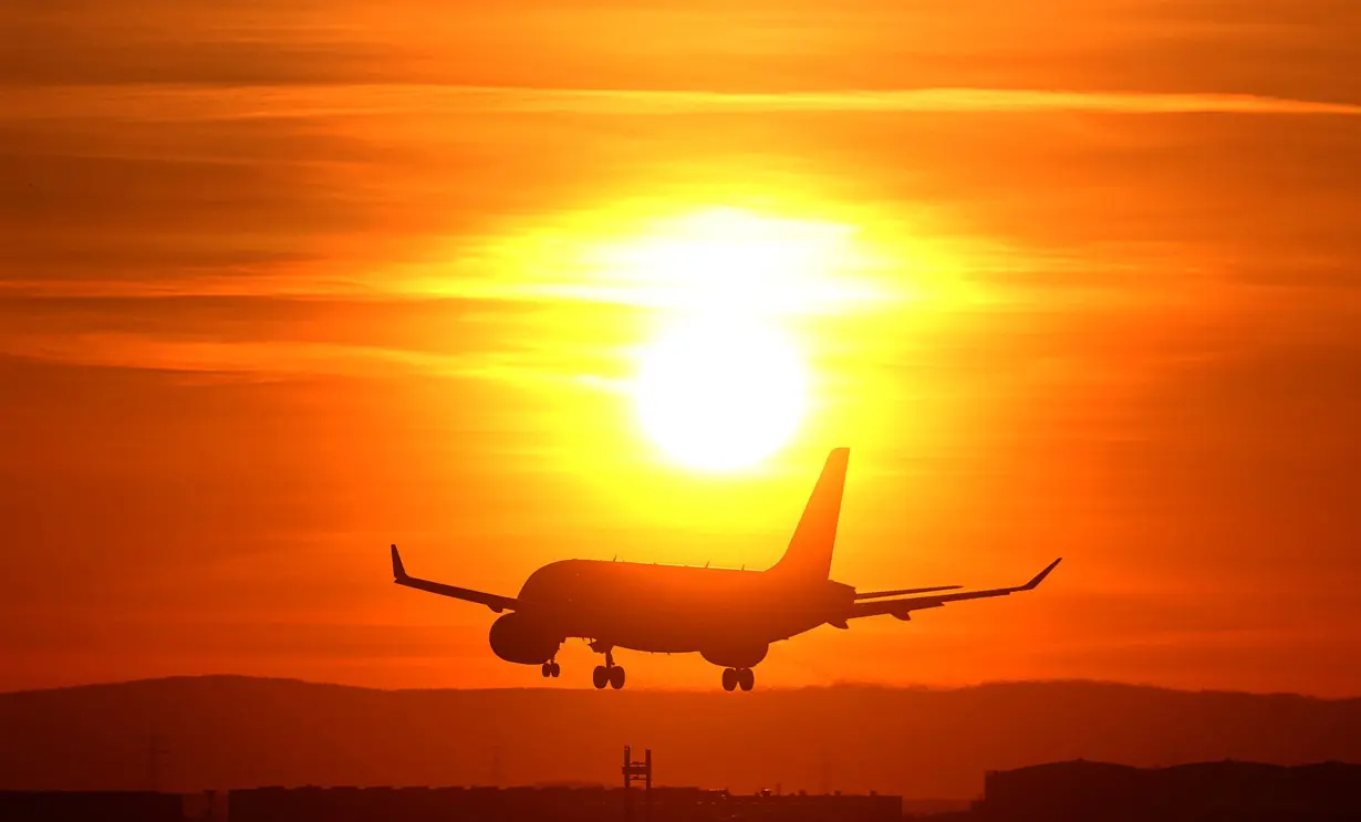 An airplane lands during sunset