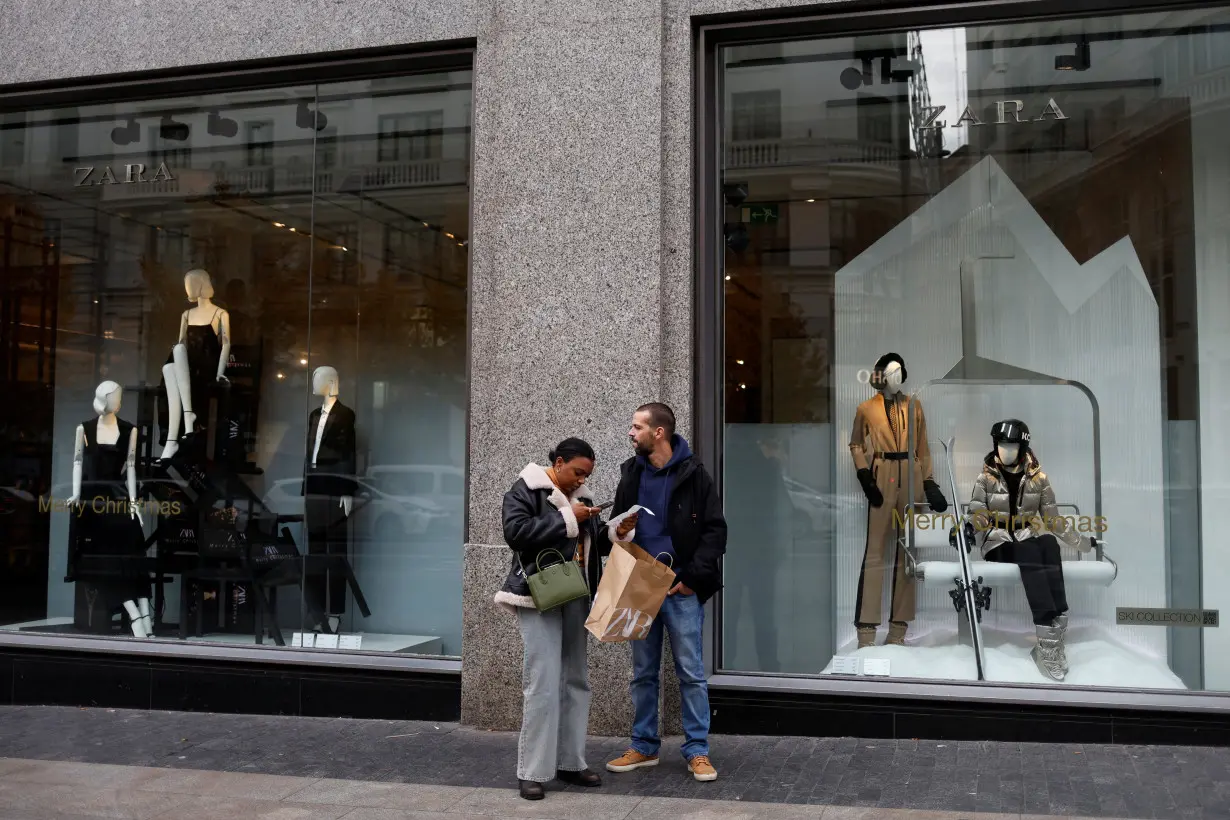 A woman takes a picture of a receipt after coming out of a Zara store in central Madrid