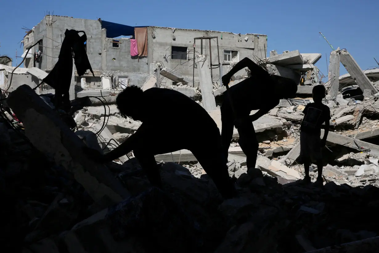 FILE PHOTO: Palestinians remove the rubble of houses destroyed by Israeli strikes, in Khan Younis