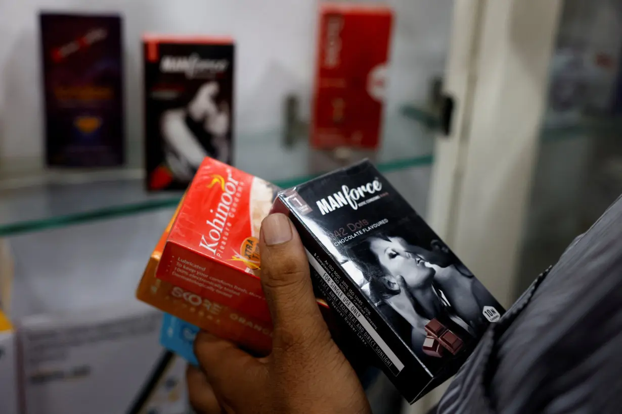 A man selects packets of condoms that are displayed for sale at a chemist shop in Ahmedabad