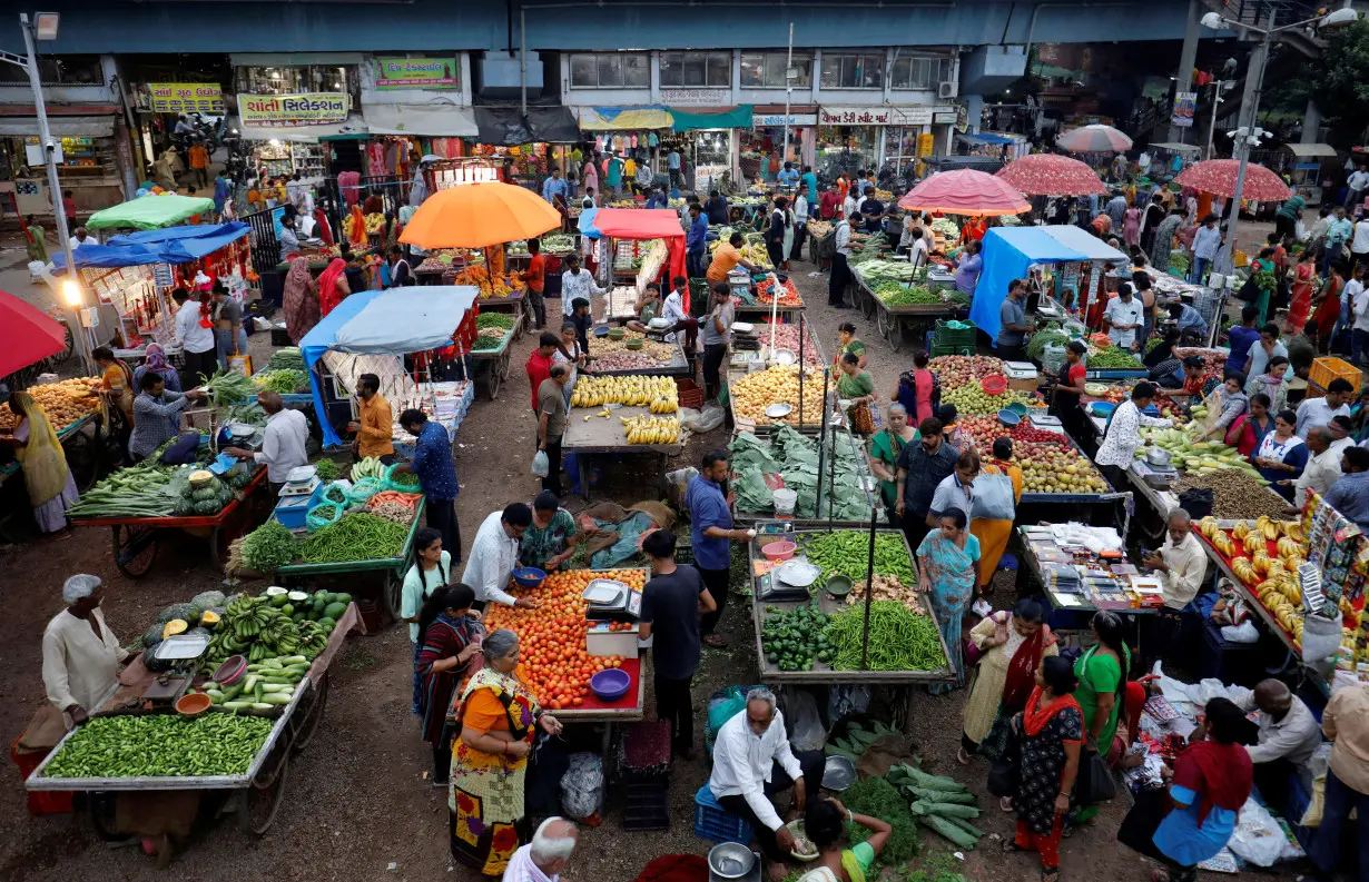 Customers buy fruits and vegetables at an open air evening market in Ahmedabad