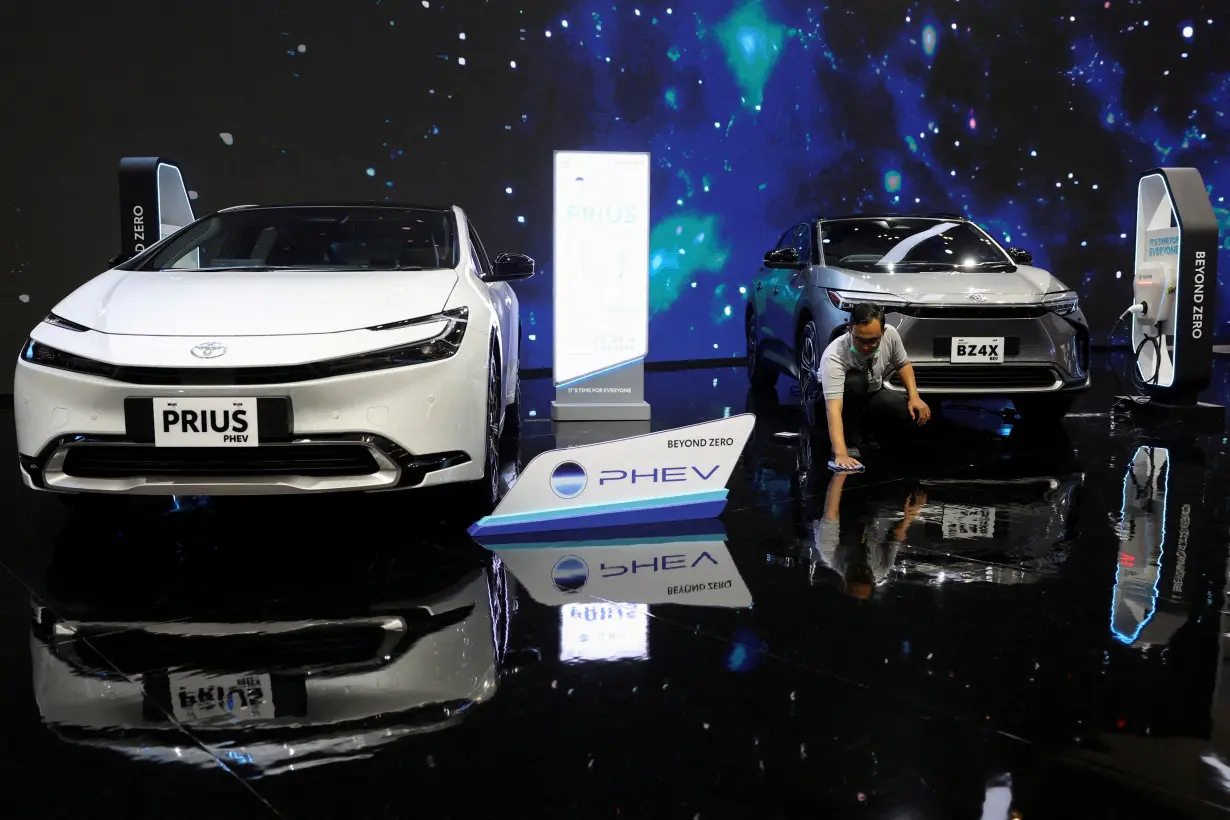 FILE PHOTO: A man wipes the floor near the Toyota Prius PHEV and Toyota BZ4X during the Indonesia International Auto Show in Tangerang