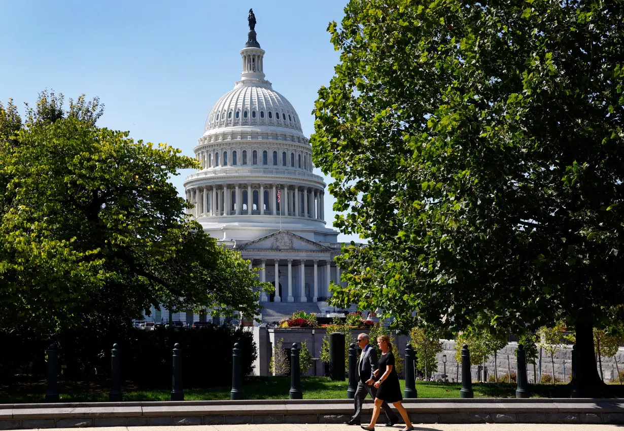 A woman and a man walk in front of the U.S. Capitol in Washington