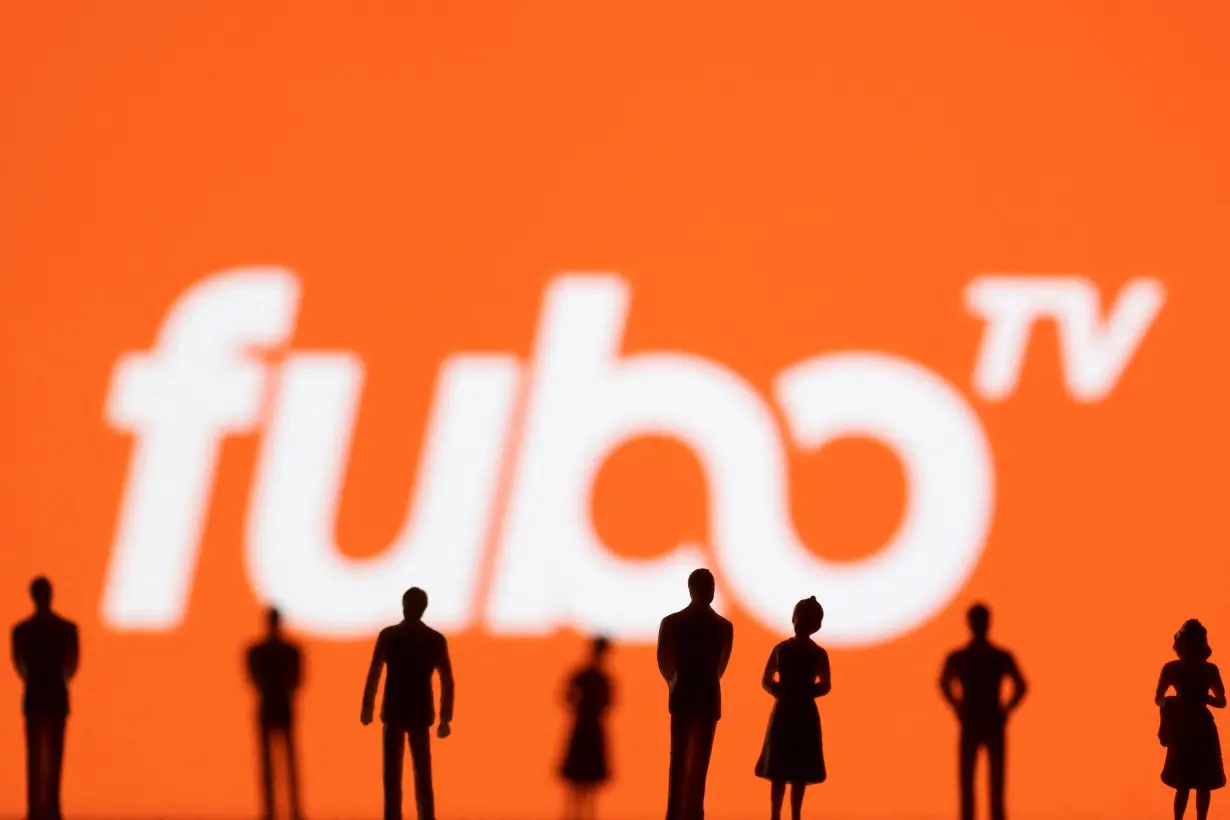 Toy figures of people are seen in front of the displayed Fubo TV logo, in this illustration