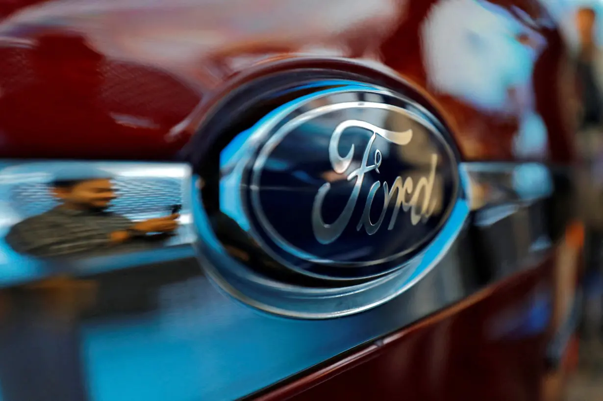 FILE PHOTO: A visitor is reflected as he takes pictures of a new Ford Aspire car during its launch in New Delhi