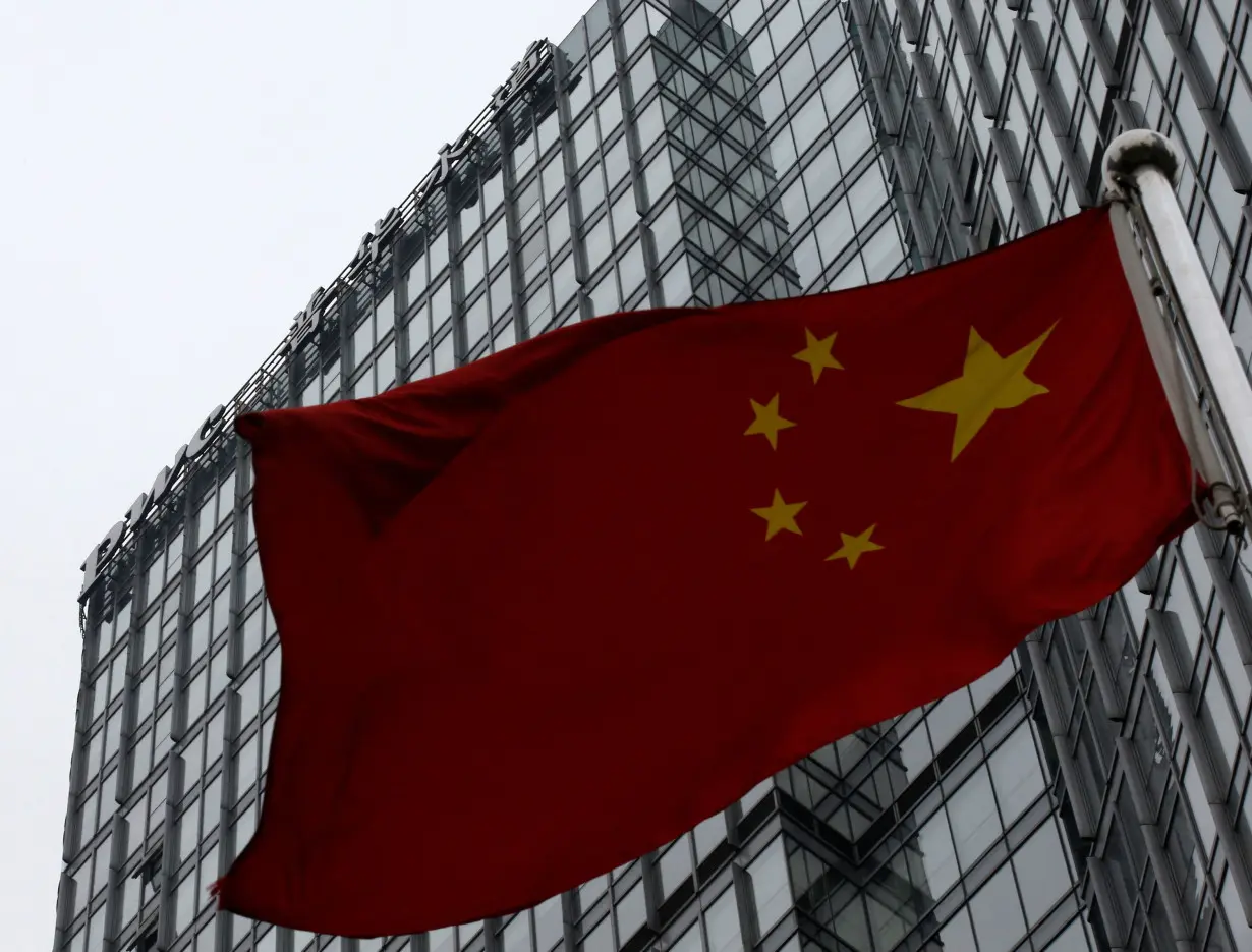 FILE PHOTO: A building housing the PricewaterhouseCoopers (PWC) branch office stands behind a Chinese national flag in Beijing