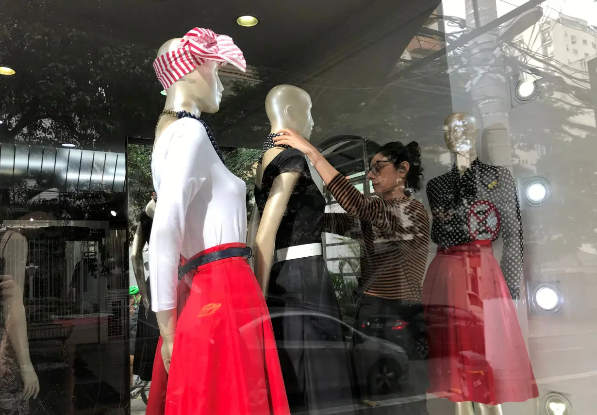 FILE PHOTO: A shop assistant arranges clothes on a mannequin in Sao Paulo