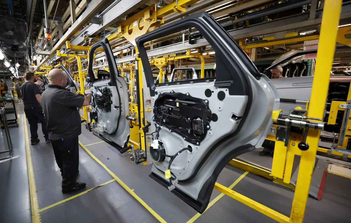 Staff members assemble door panels on the production line at Jaguar Land Rover's Halewood factory in Liverpool