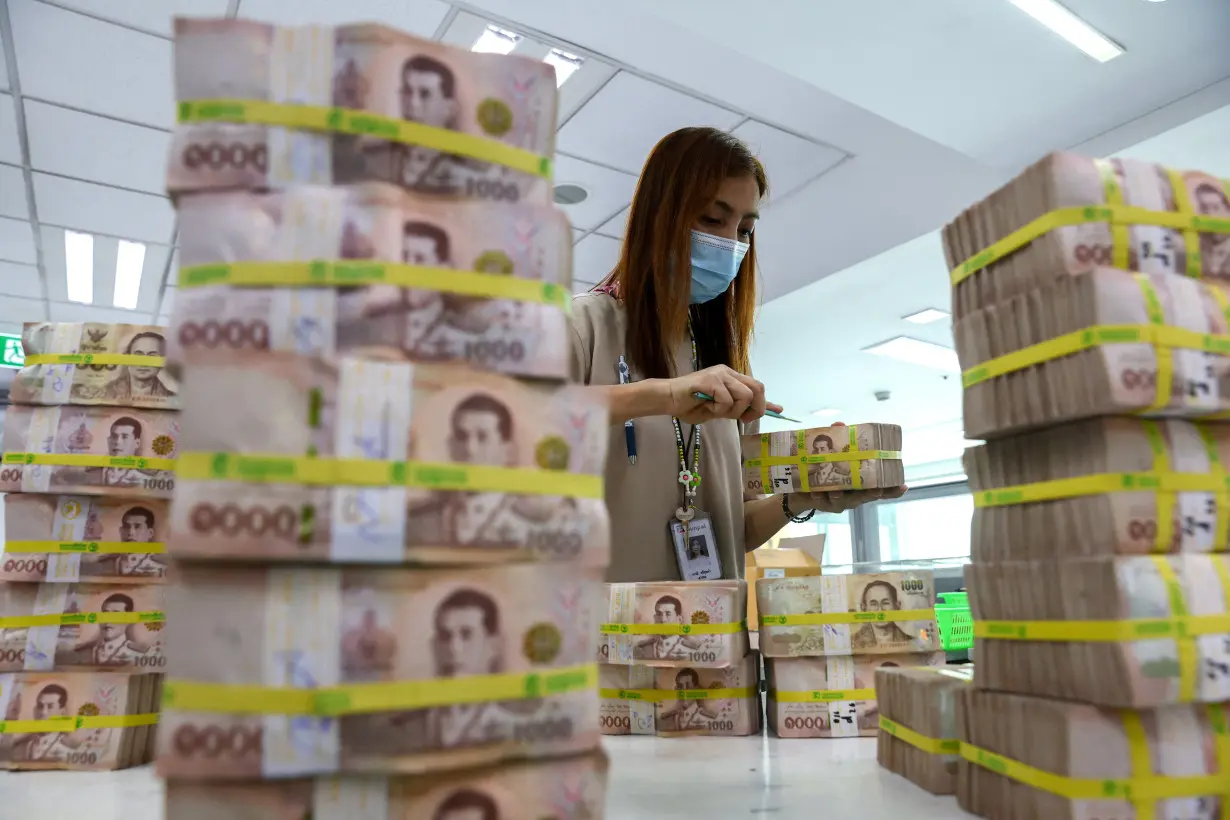 A bank employee gathers Thai baht notes at a Kasikornbank in Bangkok