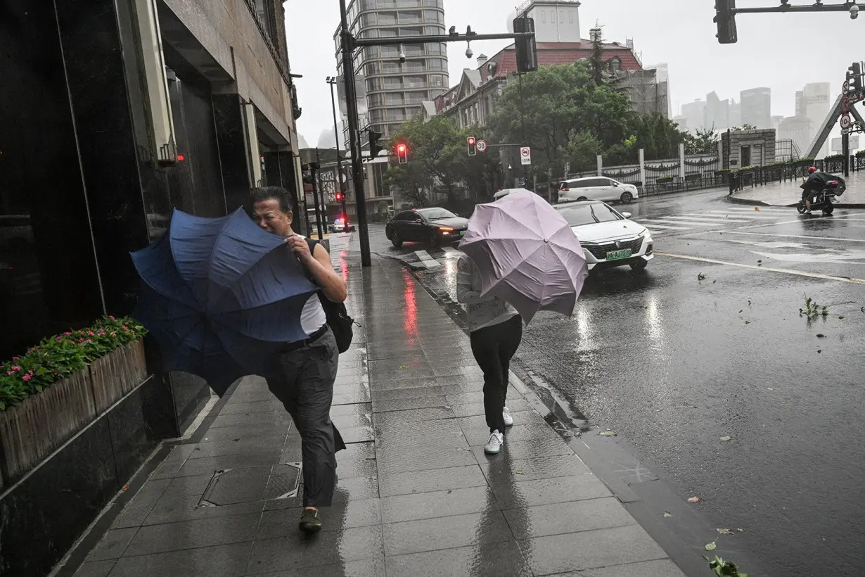 Pedestrians struggle with their umbrellas in strong winds and rain from the passage of Typhoon Bebinca in Shanghai on September 16, 2024.