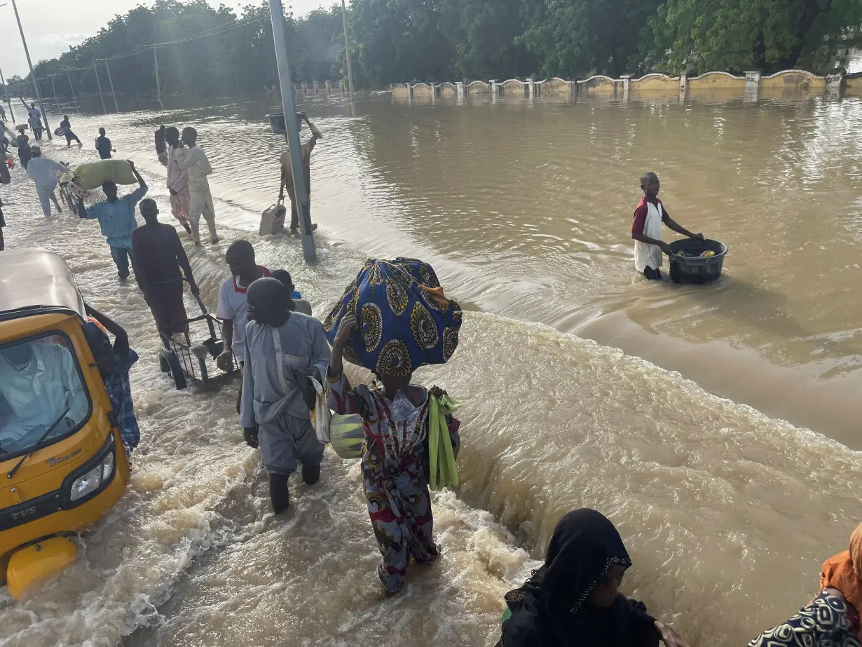 Residents leave the flooded areas with their belongings in Maiduguri