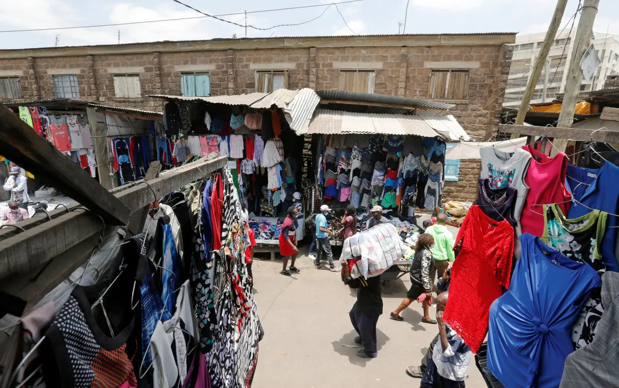 A worker carries a bale of imported second-hand clothes past displayed apparel at the Gikomba market in Nairobi, Kenya, September 18, 2020.