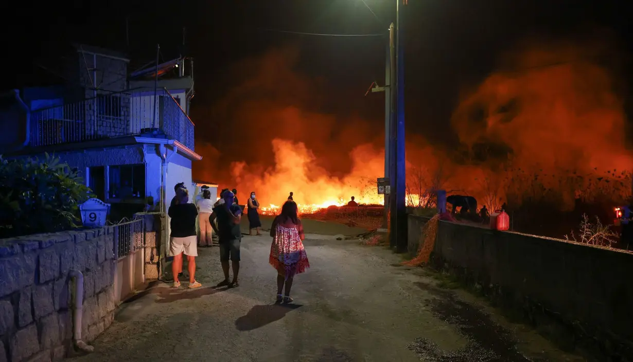 People watch a wildfire in Canas de Senhorim, Portugal.