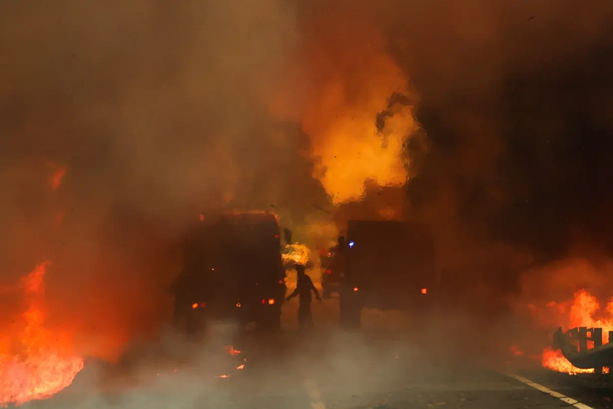 Firefighters try to extinguish a wildfire on a road in Junqueiro, Agueda