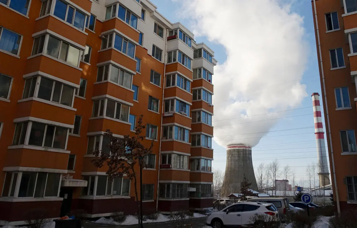 FILE PHOTO: Smoke billows from a cooling tower of a thermal power plant near residential buildings in the coal city of Hegang