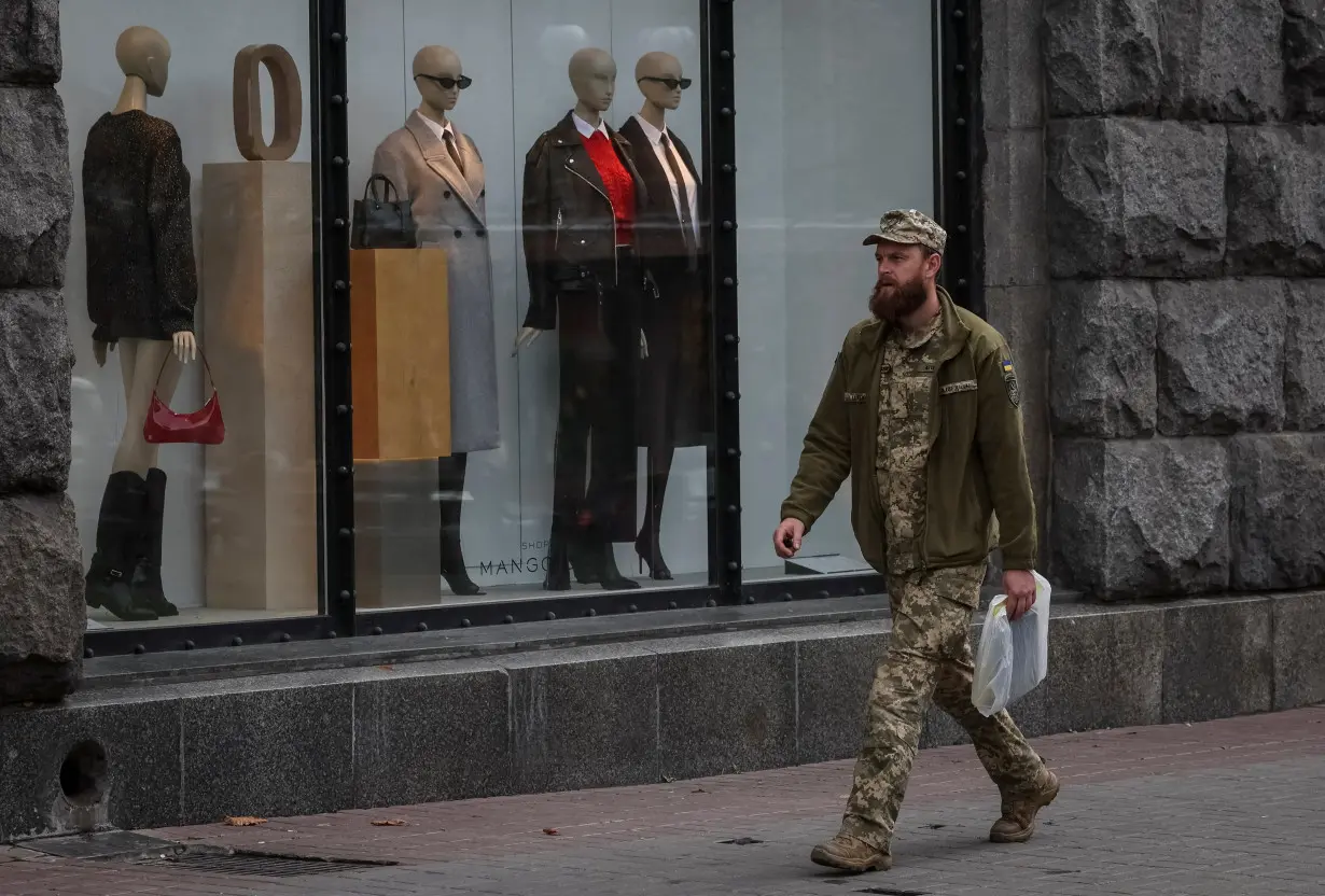 A Ukrainian seviceman walks by a shop window with mannequins in central Kyiv