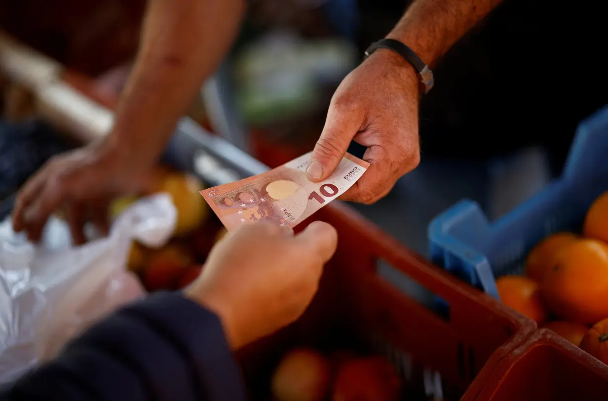 A shopper pays with a ten Euro bank note at a local market in Nantes