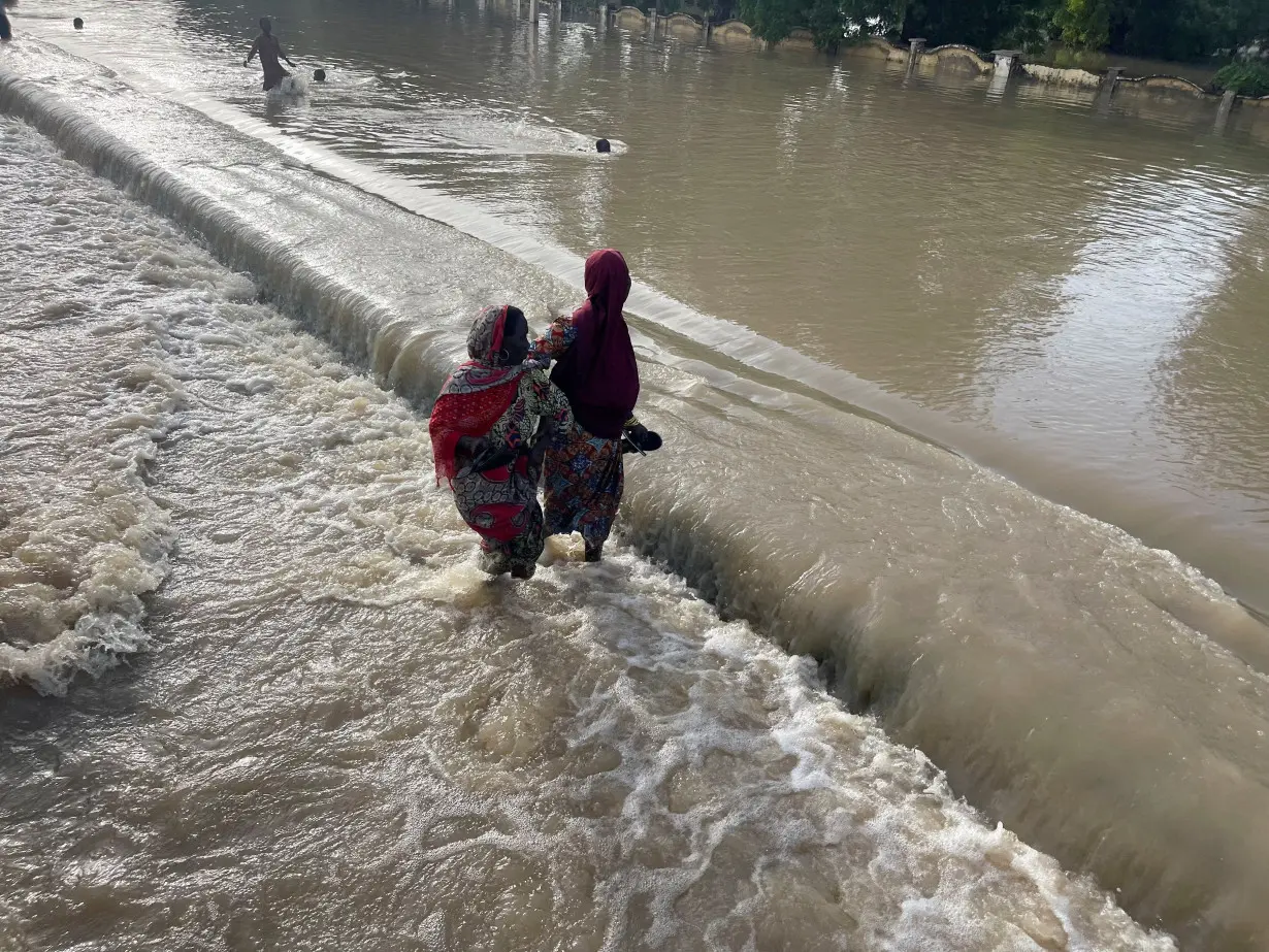 FILE PHOTO: Residents leave the flooded areas with their belongings in Maiduguri