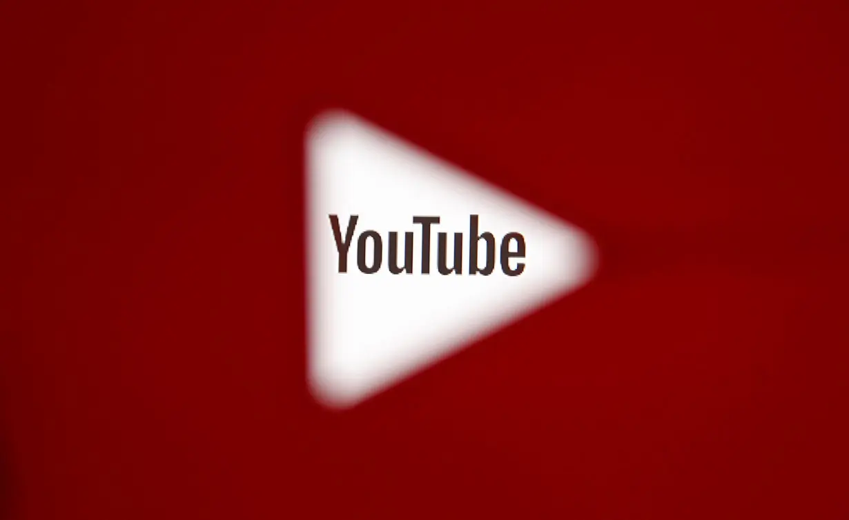 A 3D-printed YouTube icon is seen in front of a displayed YouTube logo in this illustration