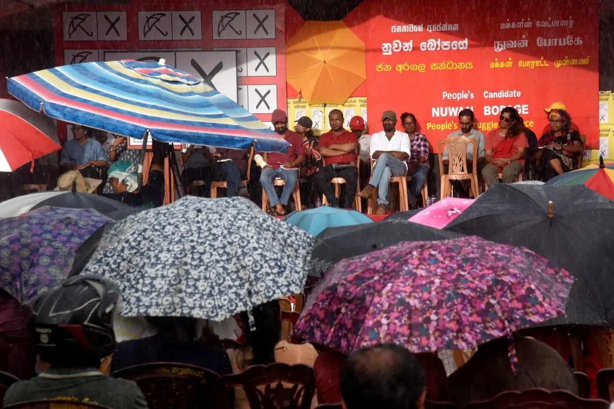 Supporters of Nuwan Bopage use umbrellas as it drizzles during an election campaign rally ahead of the presidential election, in Homagama