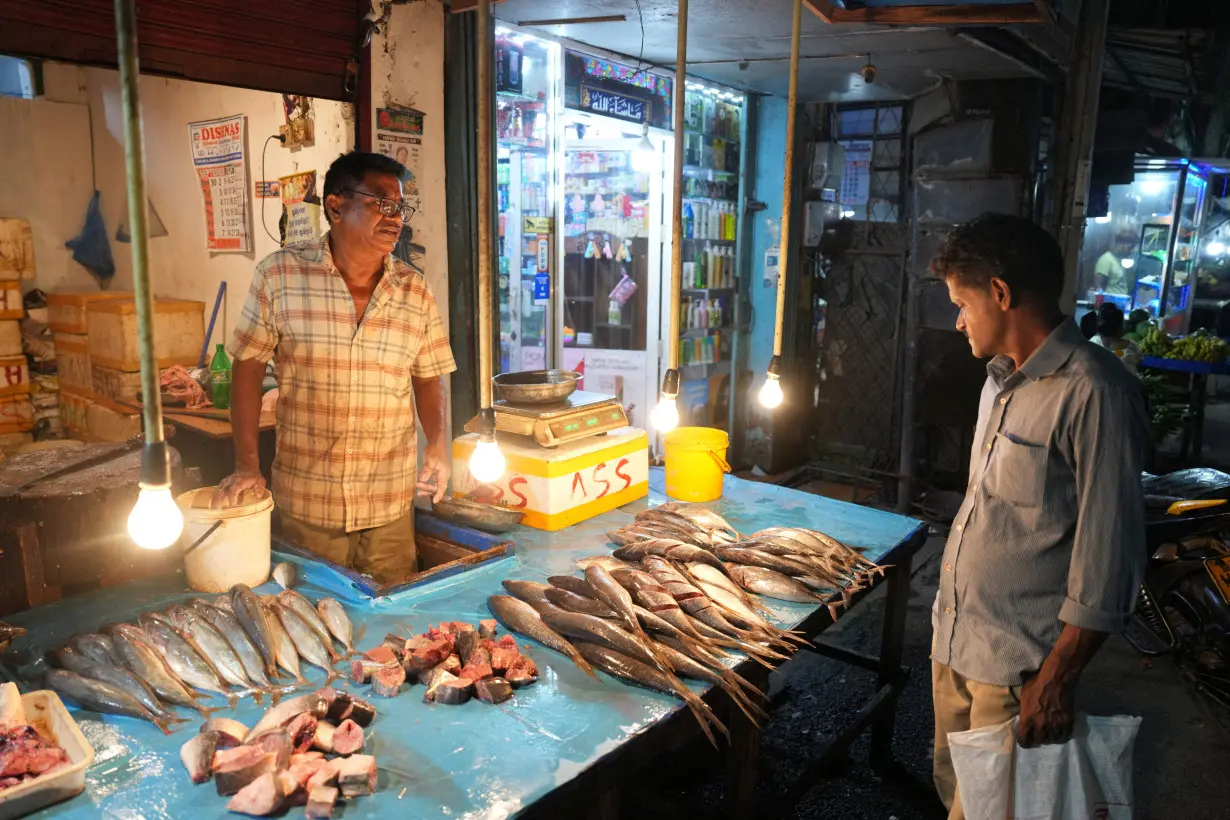 W.A. Jayantha speaks with a customer at his shop along a street in Thotalanga, Colombo