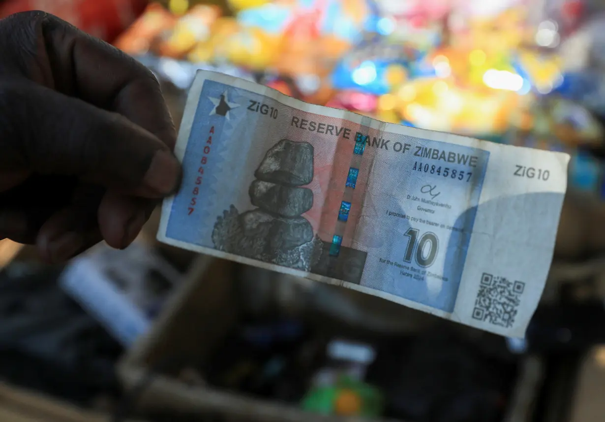 A vendor shows a ten Zimbabwe gold-backed (ZiG) note along a street in Harare