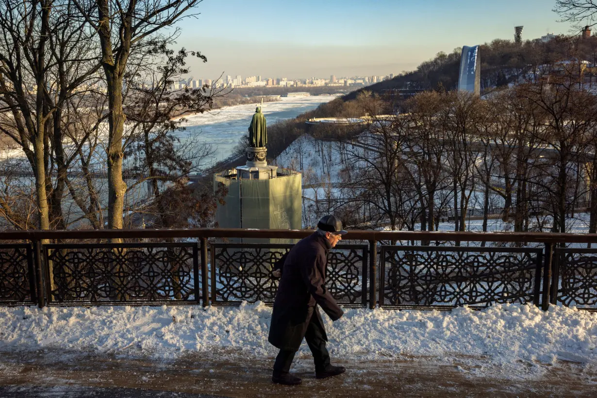 A man walks in a park overlooking Dnipro River on a sunny winter day in Kyiv