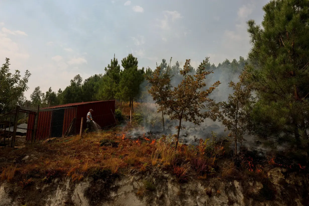 A man waters a terrain during a wildfire in Castro Daire