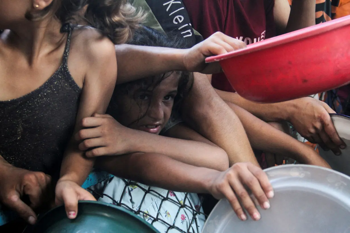 FILE PHOTO: Palestinians wait to receive food cooked by a charity kitchen in the northern Gaza Strip