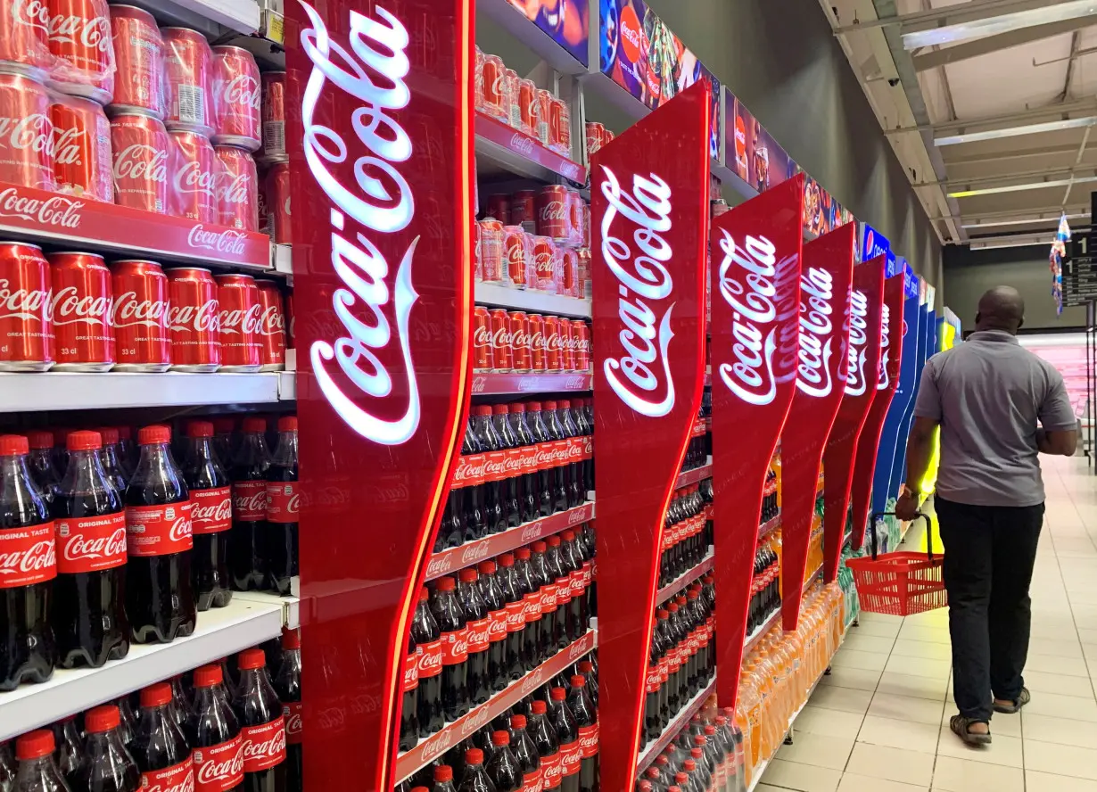 FILE PHOTO: A man walks past shelves of Coca-Cola bottles and cans at a Shoprite store inside Palms shopping mall in Lagos