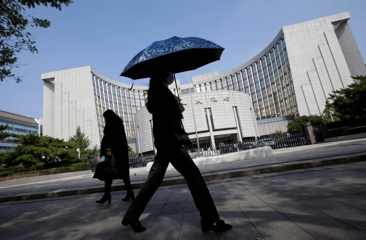 FILE PHOTO: FILE PHOTO: People walk past the headquarters of the PBOC, the central bank, in Beijing