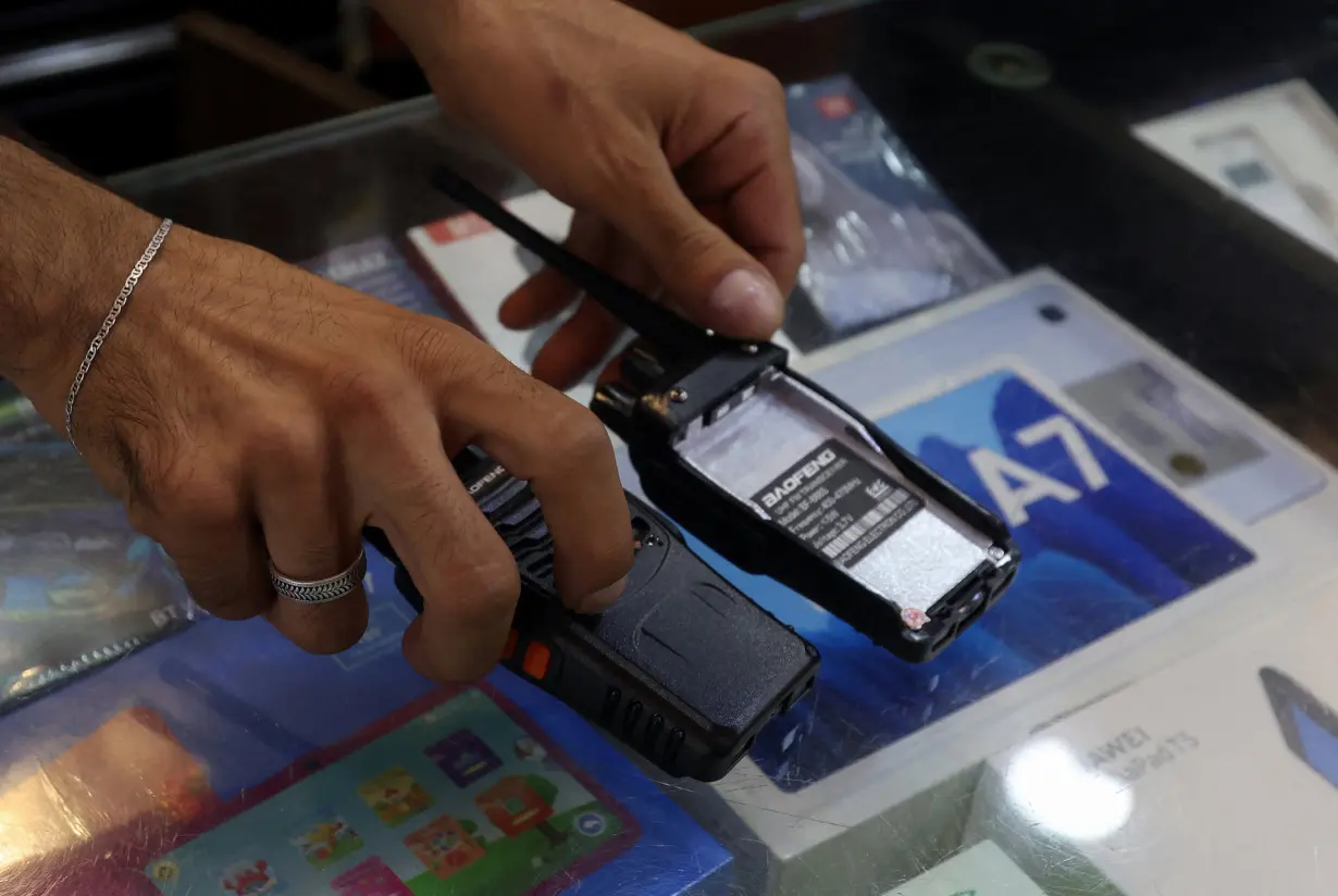 A vendor shows walkie-talkie devices without batteries at an electronic store in Sidon