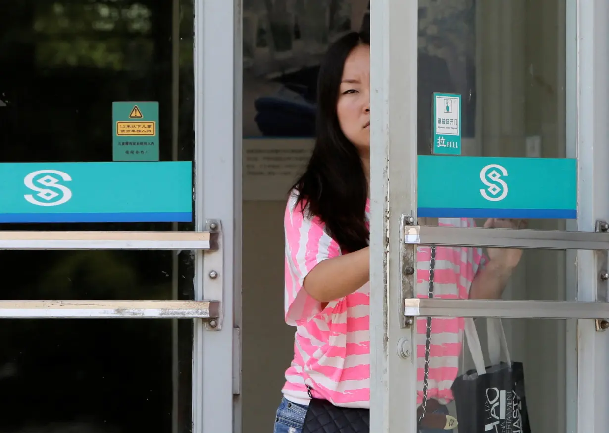 FILE PHOTO: A customer opens the door to a branch of China Minsheng Bank in Beijing