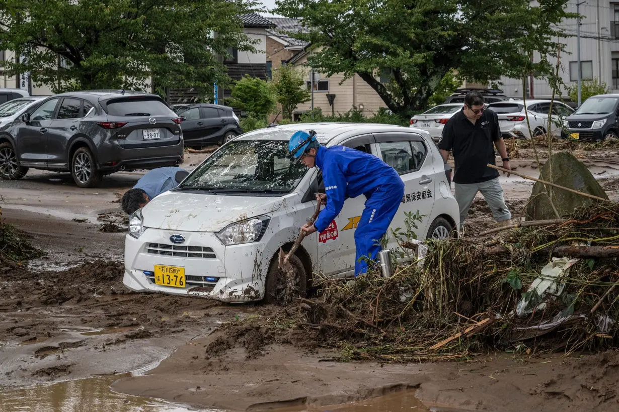 People remove mud to dislodge a car following flooding in Wajima city, Ishikawa prefecture on September 22.