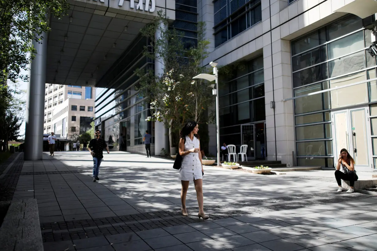 FILE PHOTO: A woman walks near high-rise buildings in the high-tech business area of Tel Aviv