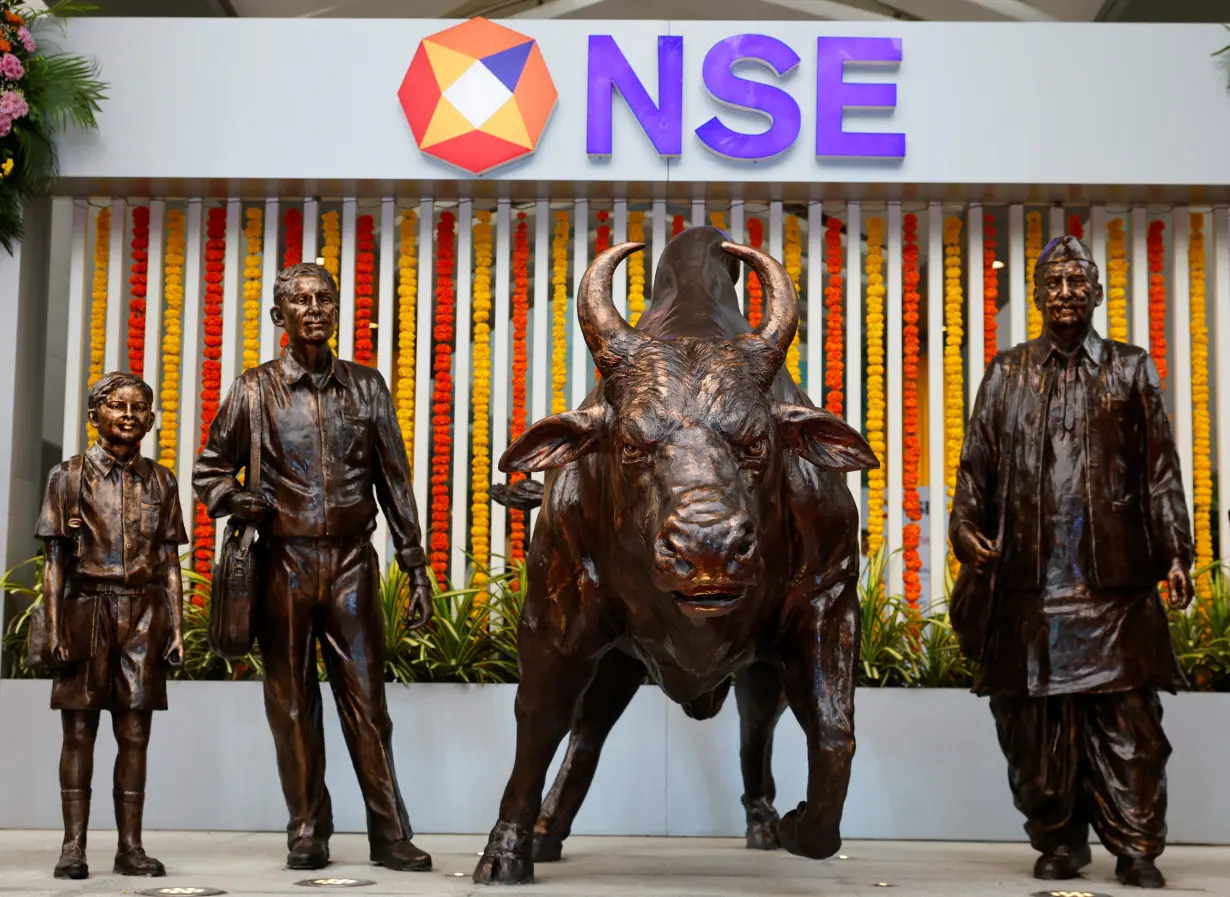 Statues of people and a bull are seen next to the logo of the National Stock Exchange (NSE) in Mumbai