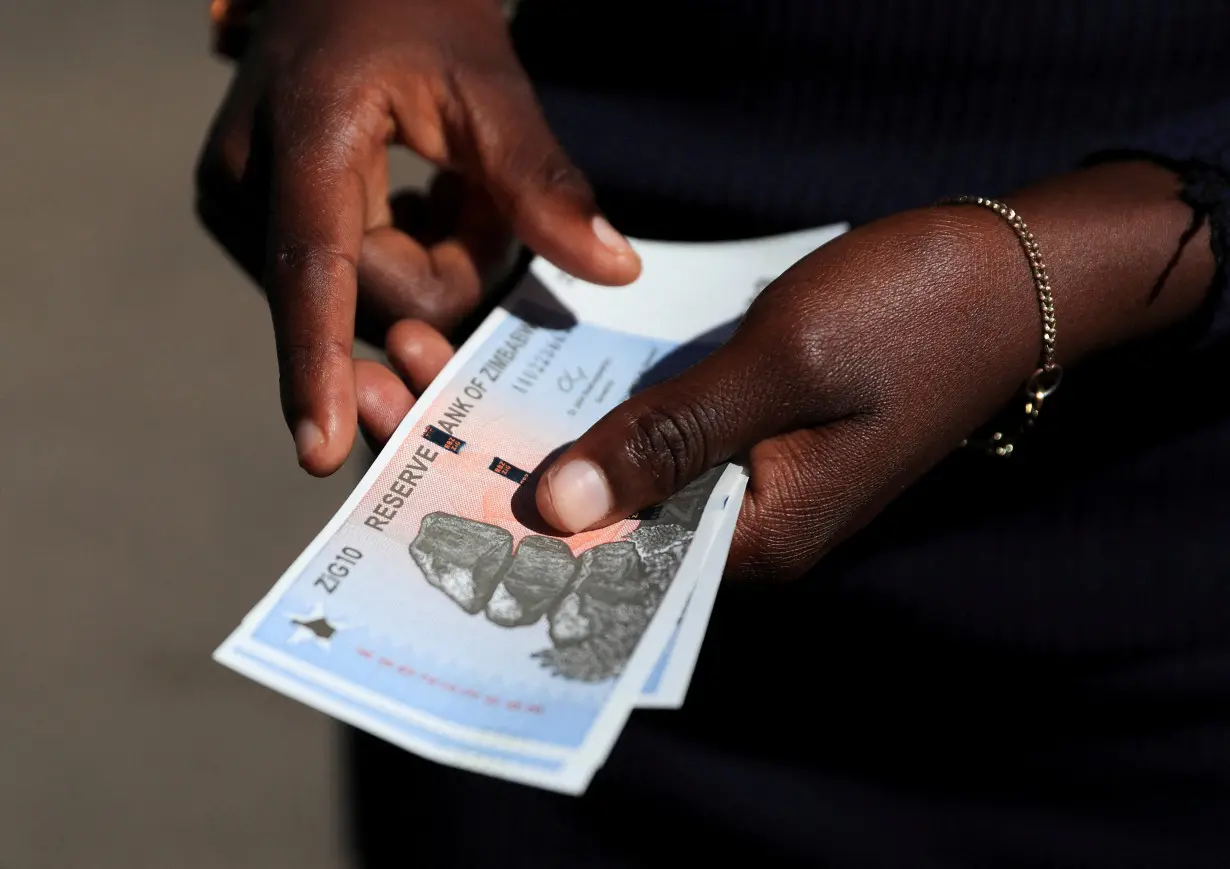 FILE PHOTO: A man shows new Zimbabwe gold-backed currency after withdrawing from a local bank in Harare