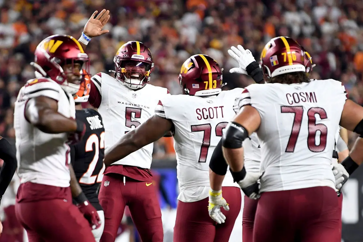 Jayden Daniels (5) celebrates throwing a touchdown pass to offensive tackle Trent Scott (73) against the Cincinnati Bengals.