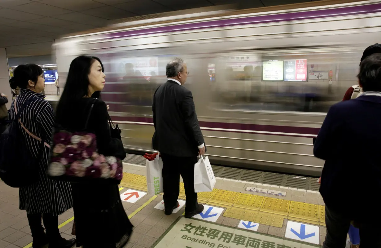 FILE PHOTO: Commuters wait for a train in Osaka