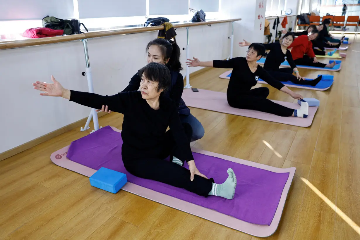 FILE PHOTO: A teacher coaches an elderly person during a yoga class in Beijing