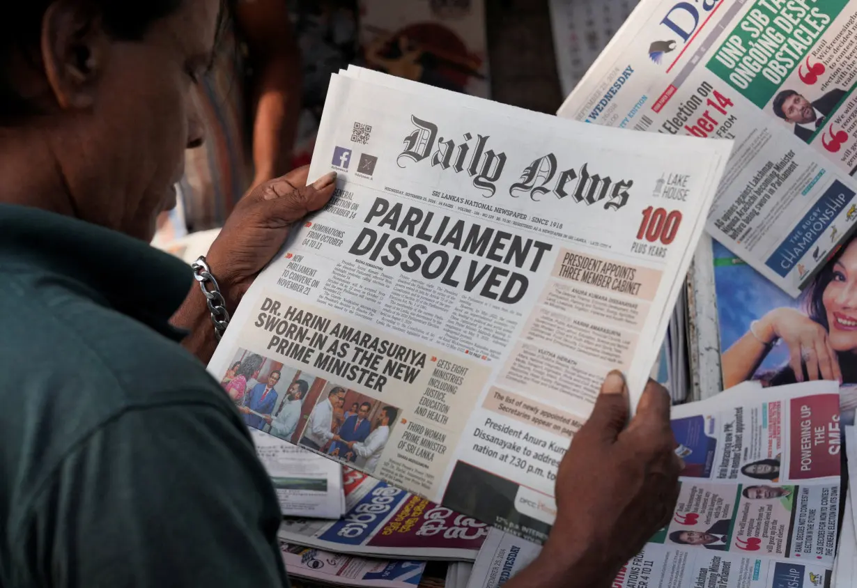 A person reads a newspaper following the appointment of Harini Amarasuriya as the new Prime Minister of Sri Lanka at a stall in Colombo