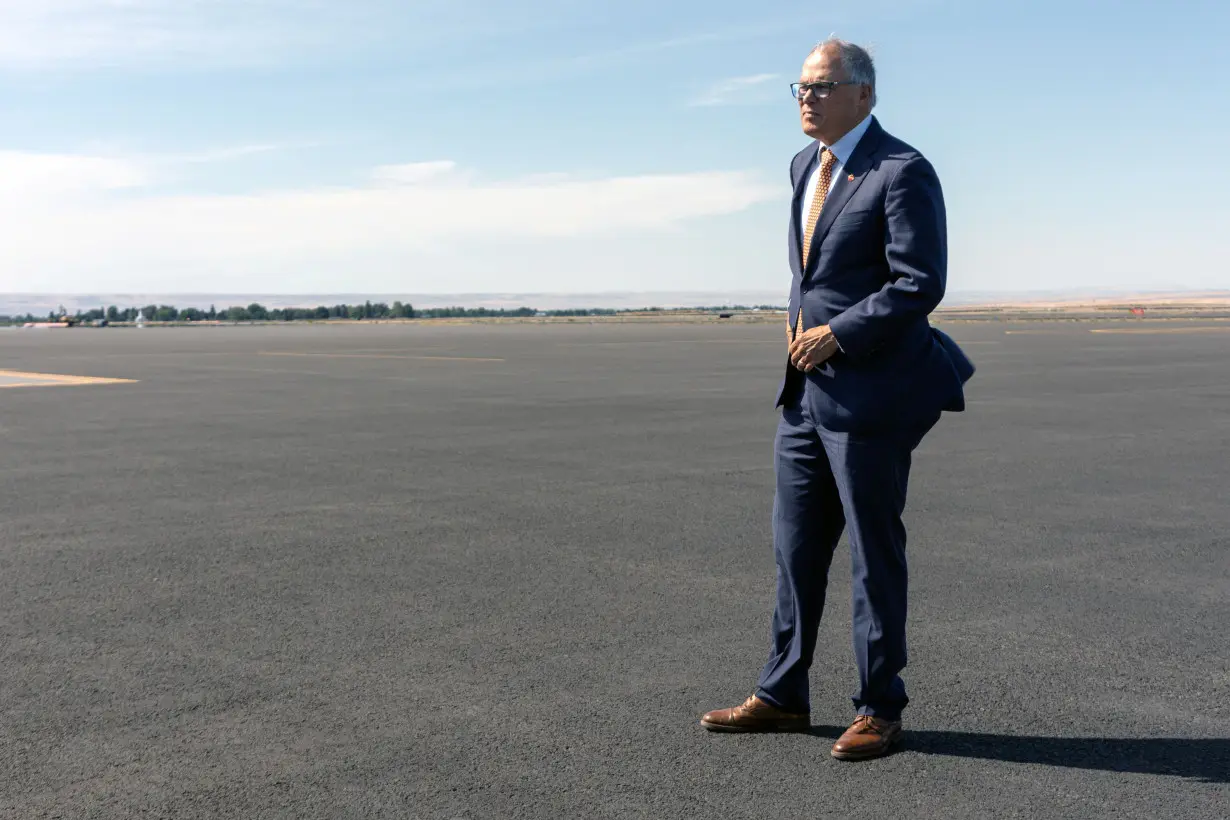 Washington Governor Jay Inslee stands on the tarmac while traveling to an event in Walla Walla, Washington