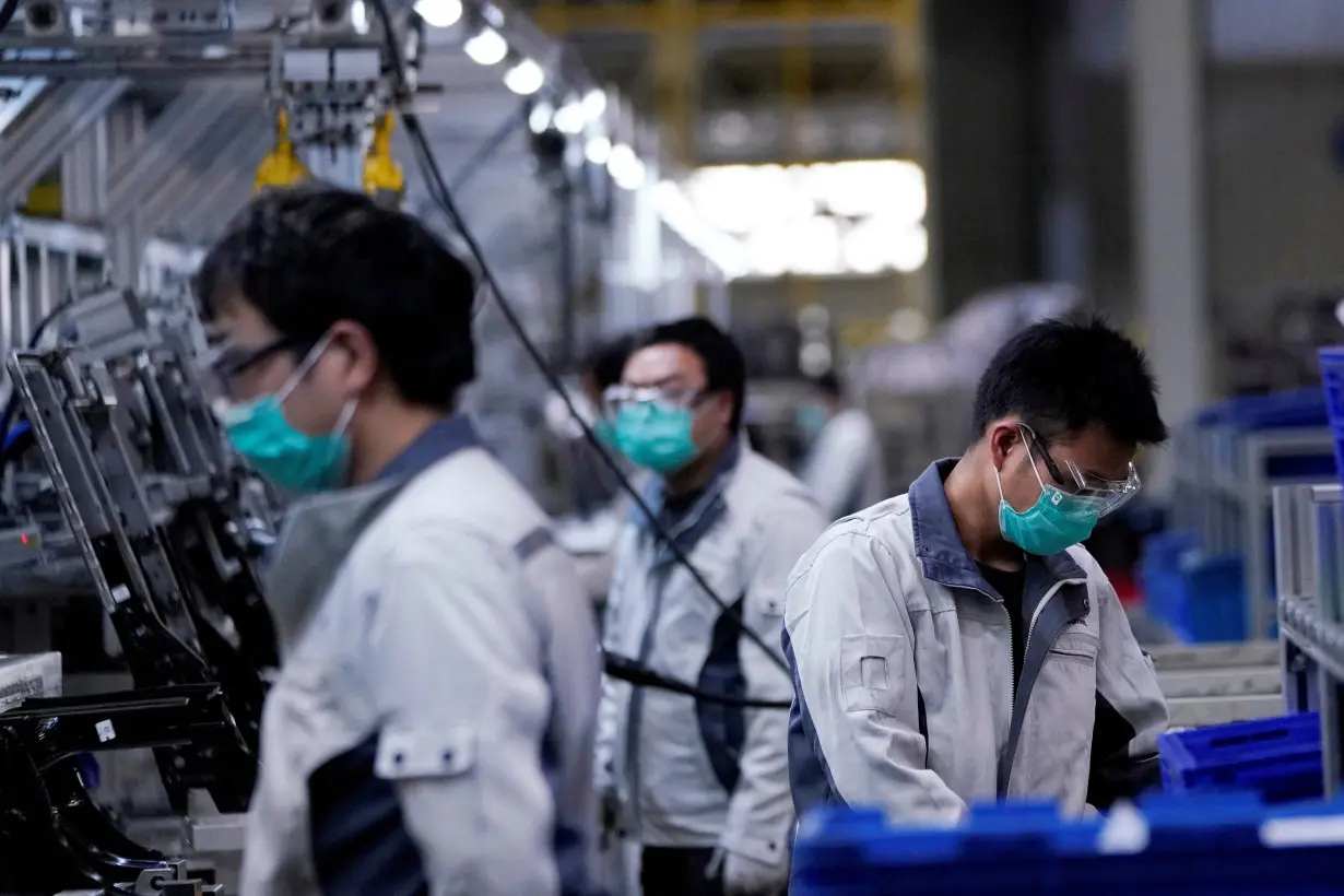 FILE PHOTO: FILE PHOTO: Employees wearing face masks work on a car seat assembly line at Yanfeng Adient factory in Shanghai